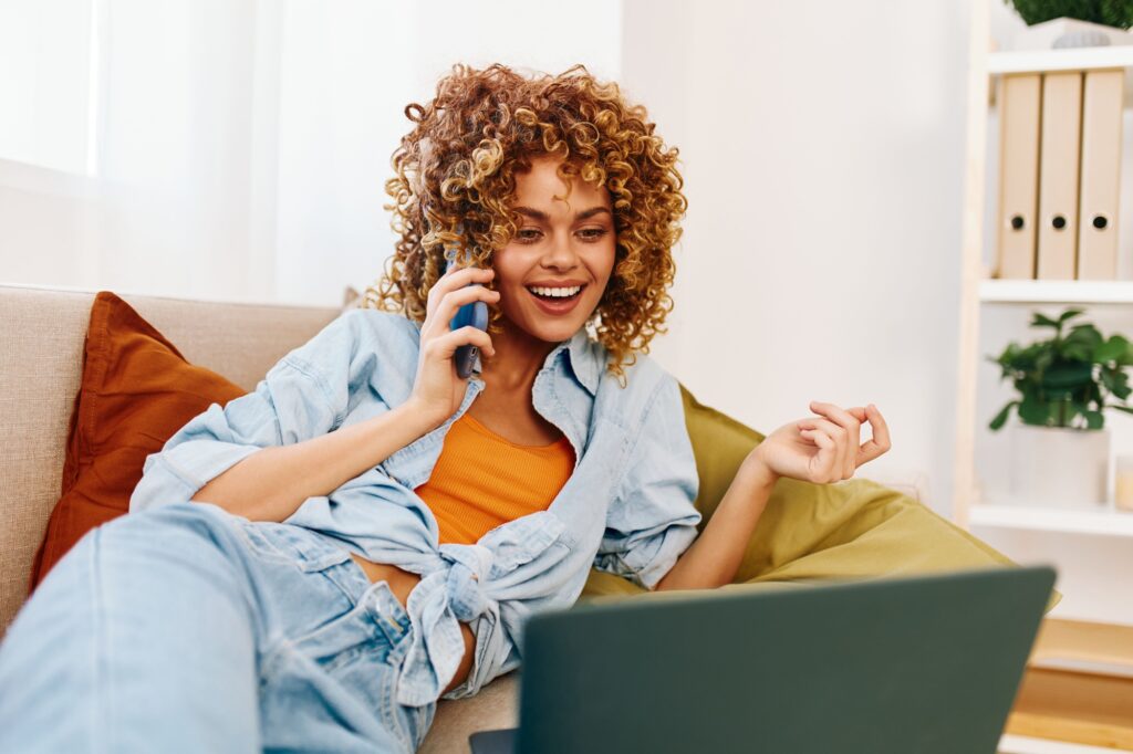 Smiling Woman Using Laptop on Cozy Sofa in Modern Living Room